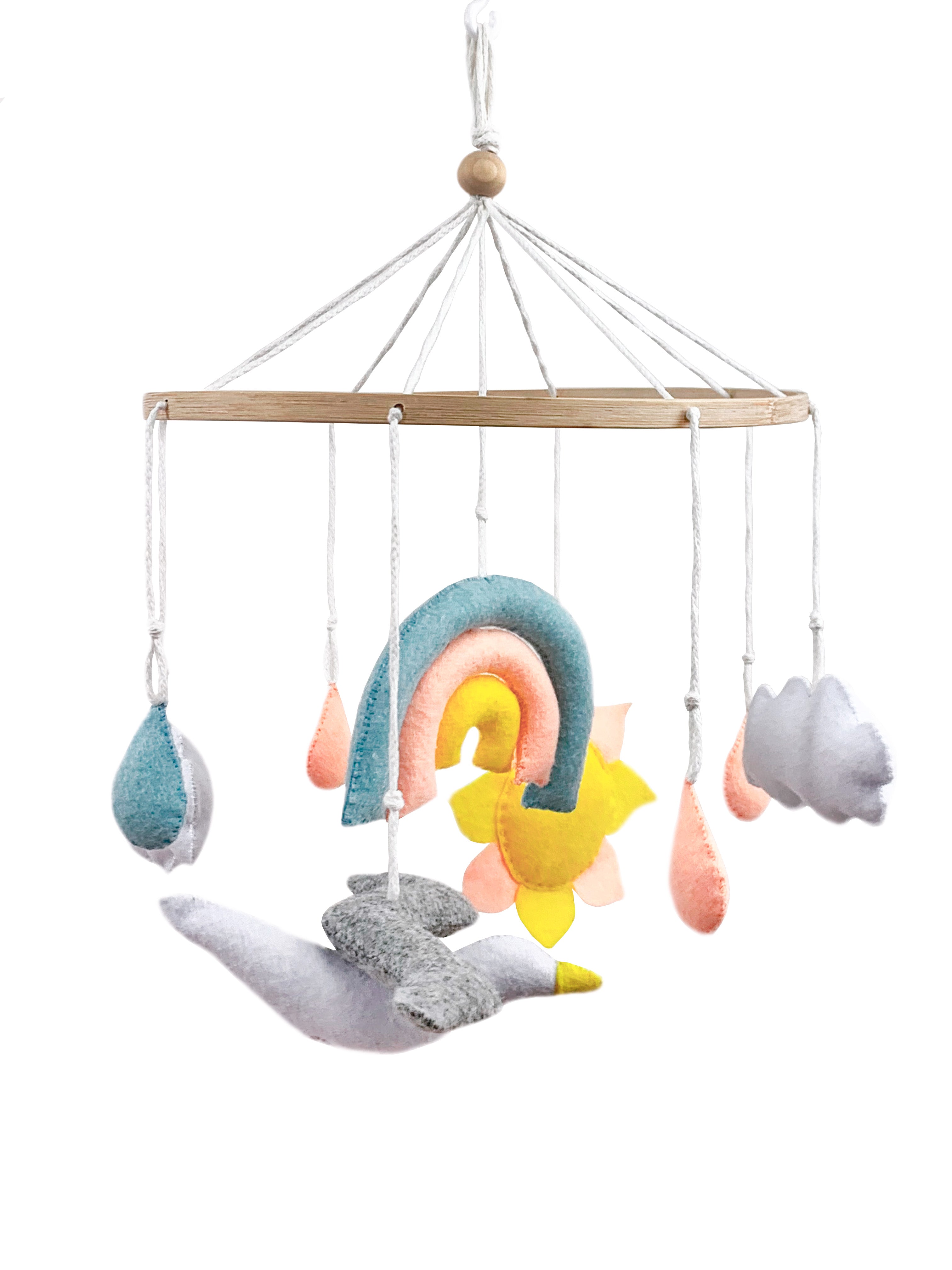 Závěsný dětský kolotoč s nebeským motivem. Na dřevěném kruhu visí ručně šité filcové dekorace: duha v pastelových barvách, slunce, kapky deště, obláčky a létající ptáček. Celý kolotoč je zavěšený na bílých šňůrách s dřevěnou kuličkou uprostřed.
